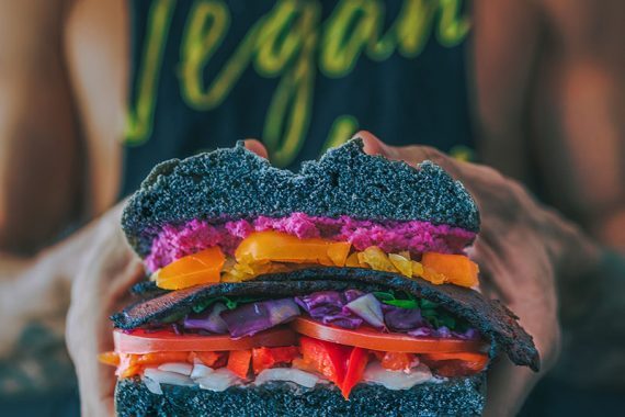 Afbeelding van een man die een vegan broodje vasthoudt.