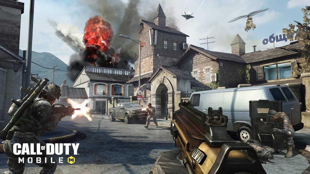 A screenshot from the game Call of Duty Mobile. The screenshot features a POV shot of a player attacking soldiers in a war-torn village, with team mates on either side of them. Explosions, helicopters, and fighter jets are all happening in the sky above.